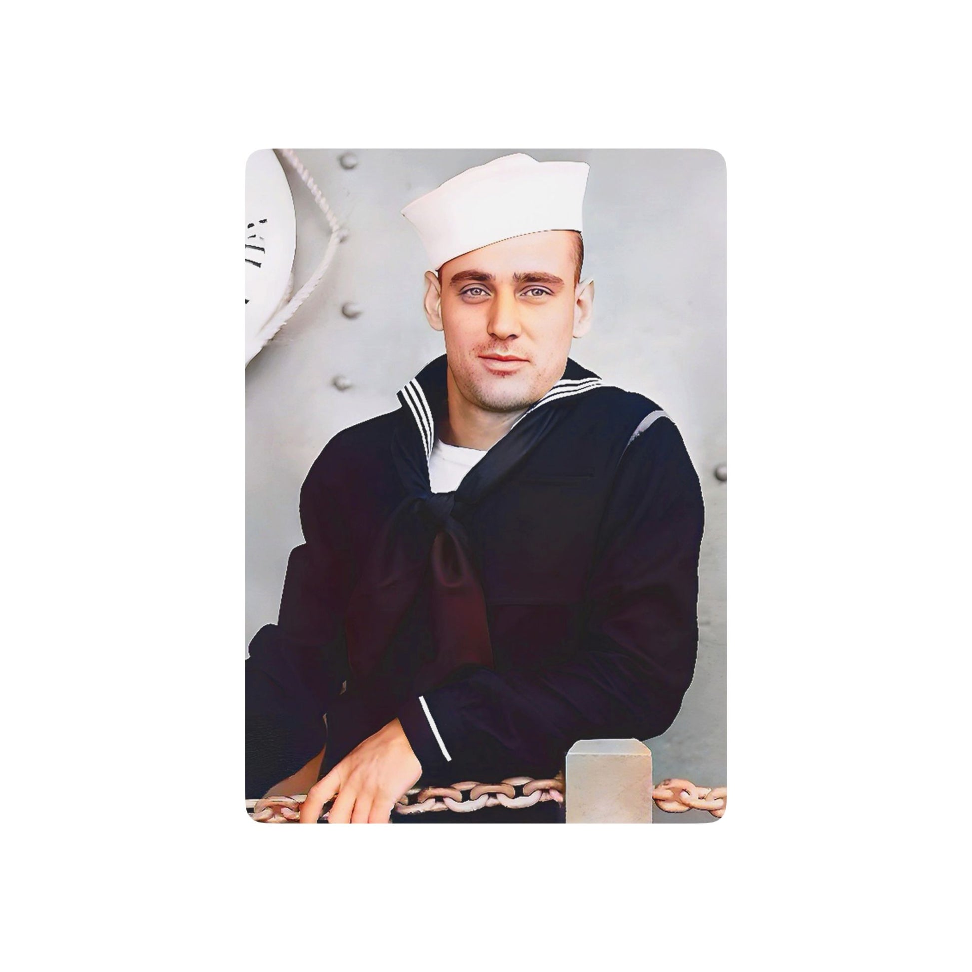 Vintage WWII photo of a U.S. Navy sailor in dress blues and a Dixie Cup hat, standing aboard a naval ship with anchor chains.