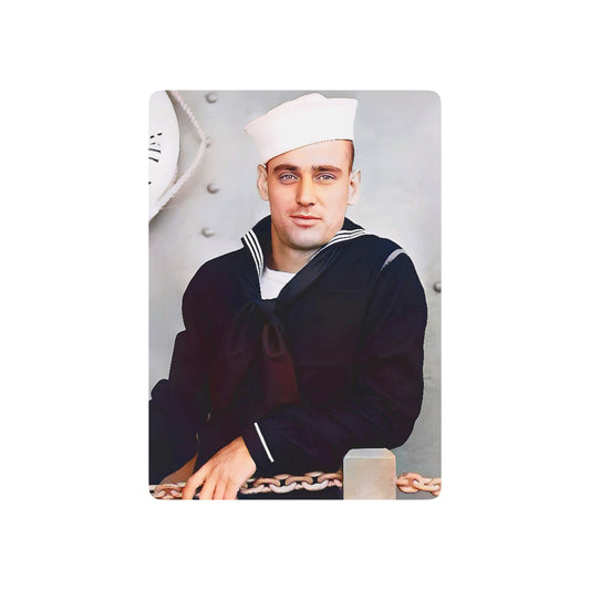 Vintage WWII photo of a U.S. Navy sailor in dress blues and a Dixie Cup hat, standing aboard a naval ship with anchor chains.