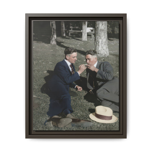 Vintage photograph wall art of two men reclining outdoors with hats on the grass and trees in the background