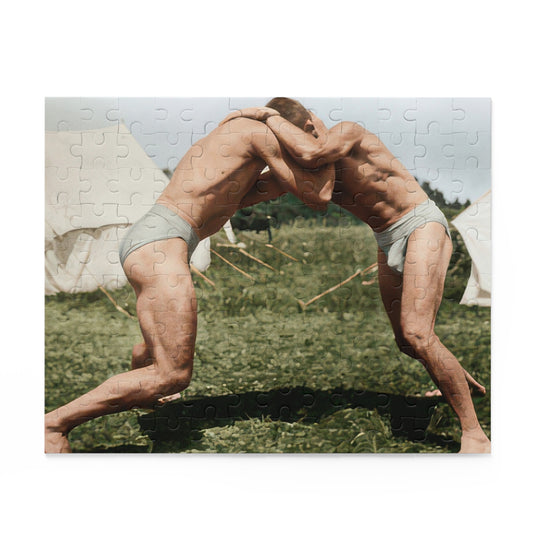 Two barefoot wrestlers in pale trunks lean into a standing clinch on grass between canvas tents, with guy ropes and a strong foreground shadow.