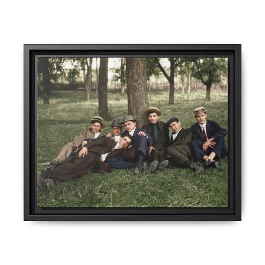 Restored historical photograph of seven men in suits seated and reclining on grass beneath mature trees.