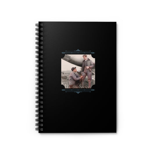 Black spiral notebook featuring a restored photo of two early 20th-century pilots sharing an intimate moment