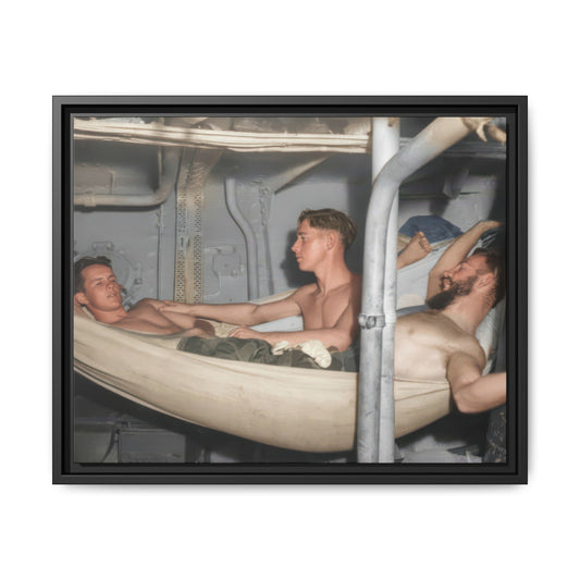 A seated shirtless man rests his hand on a reclining man’s shoulder, while a bearded man reclines in a hammock at the right.