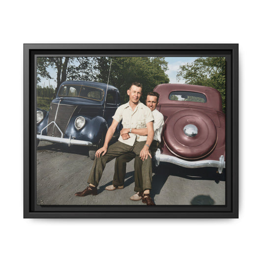 Two men seated on car bumper between vintage automobiles