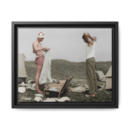 Early 20th century outdoor photograph of two young men standing beside tents and camp belongings