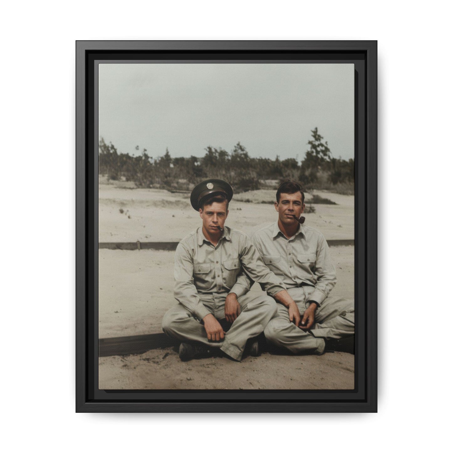 Vintage outdoor double portrait of two seated men in workwear-style shirts on sandy ground with sparse vegetation