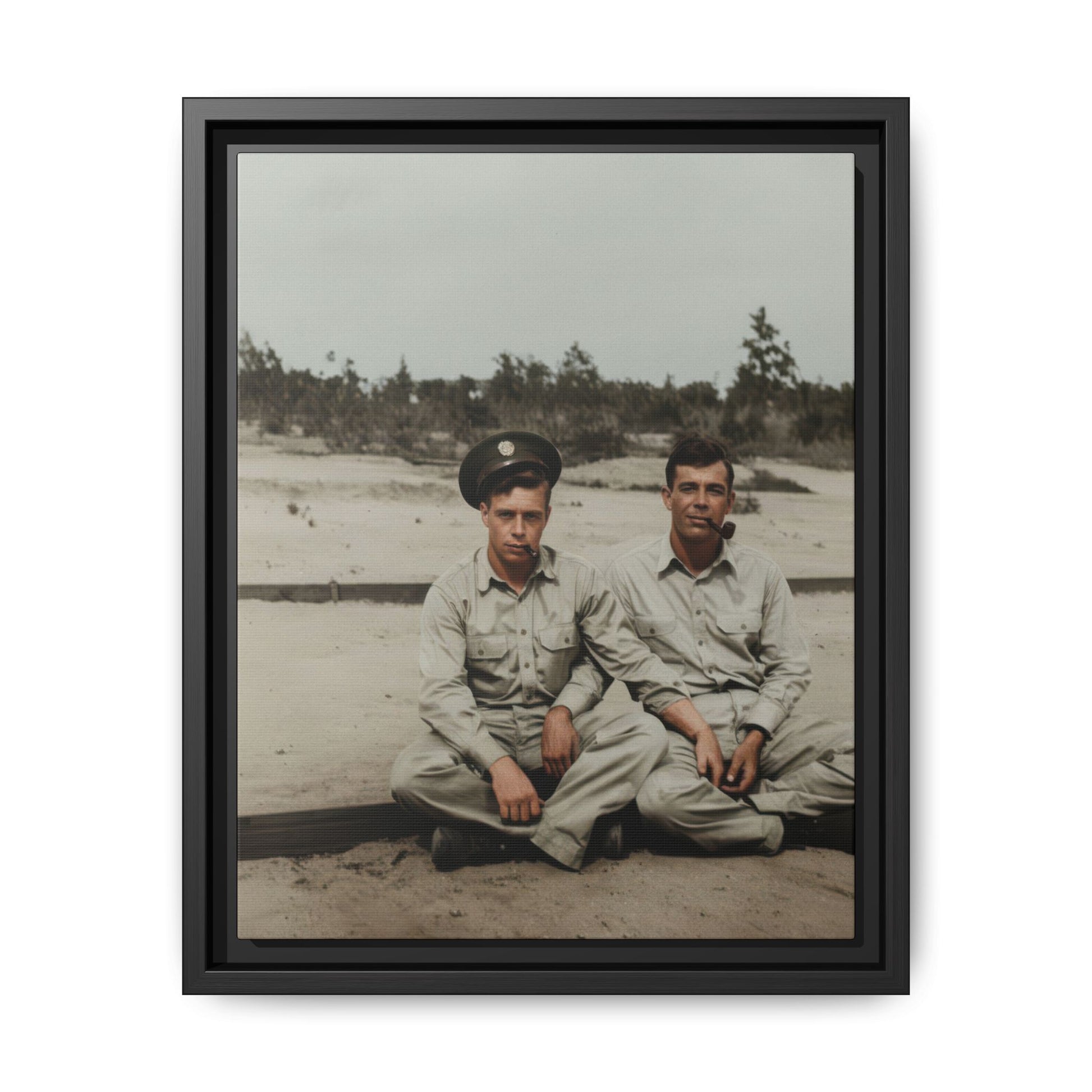 Vintage outdoor double portrait of two seated men in workwear-style shirts on sandy ground with sparse vegetation