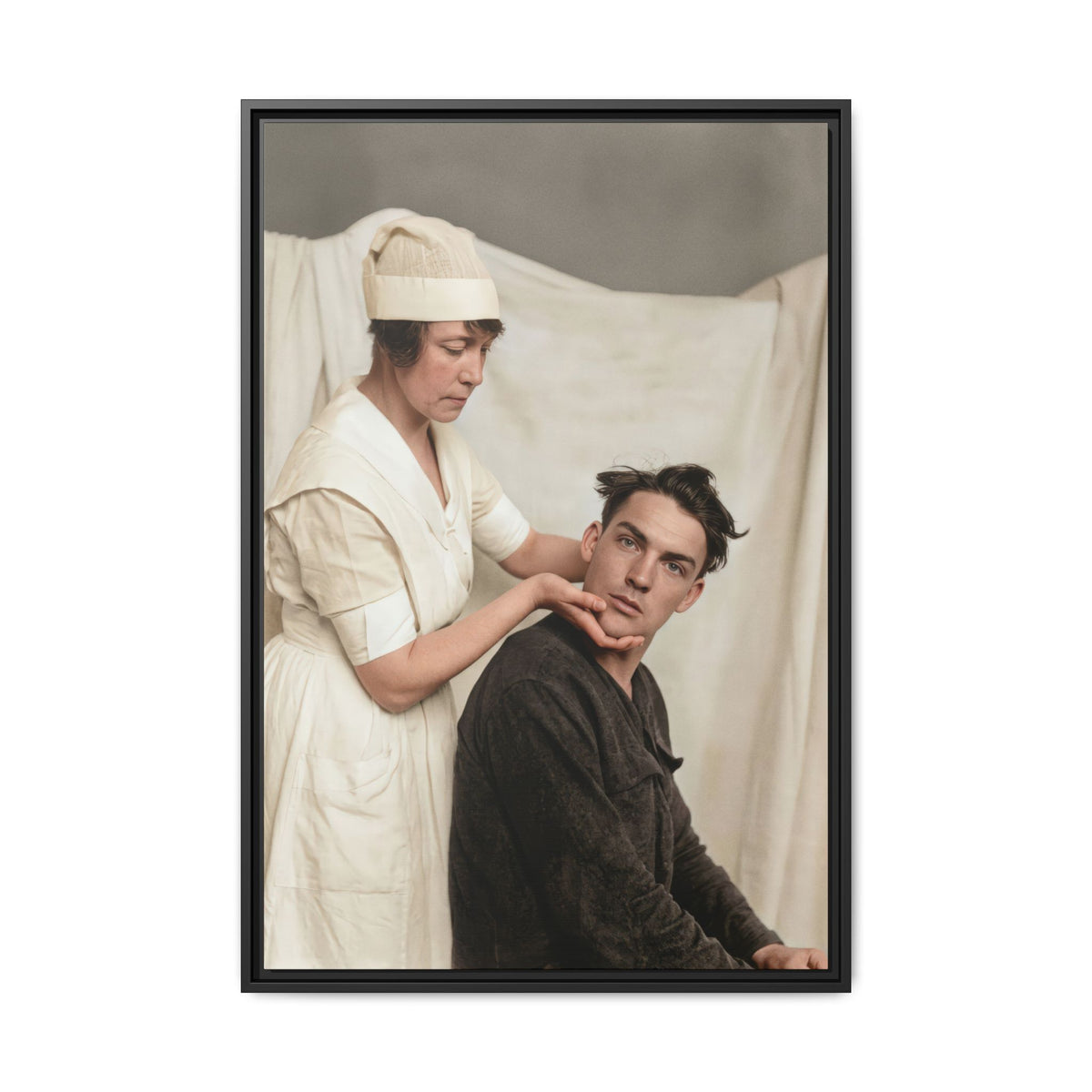 Célibataire 021 two-person scene with hands positioned beneath the man’s jaw and behind his neck before a draped fabric backdrop.