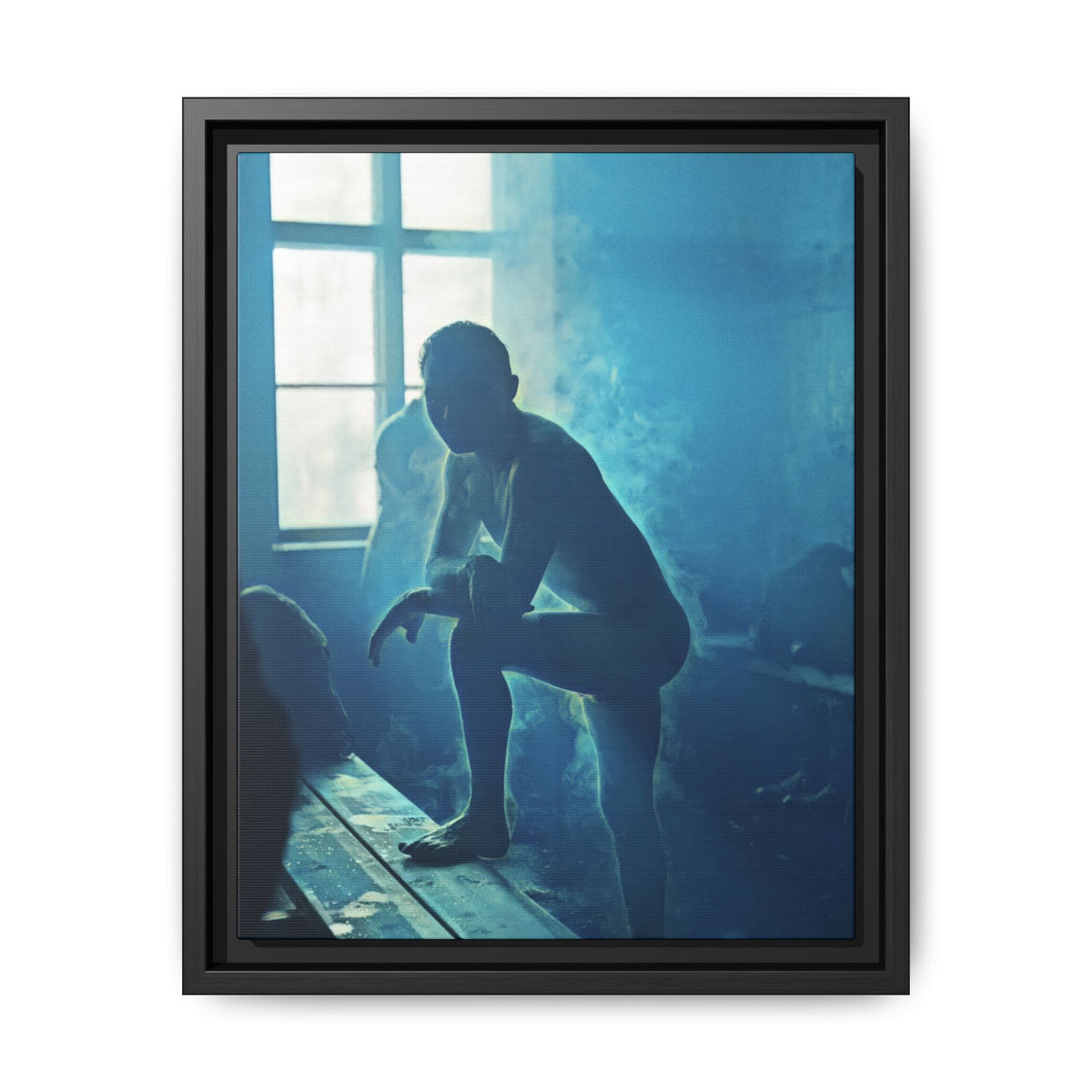 Blue-toned historical photograph of a silhouetted man leaning forward with one bare foot on a wooden bench beside a bright window.