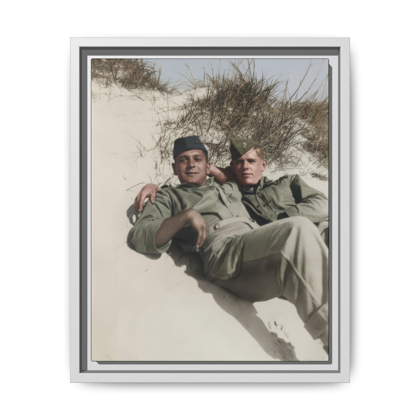Mid-century outdoor portrait of two soldiers lying together on a dune in uniform-style shirts