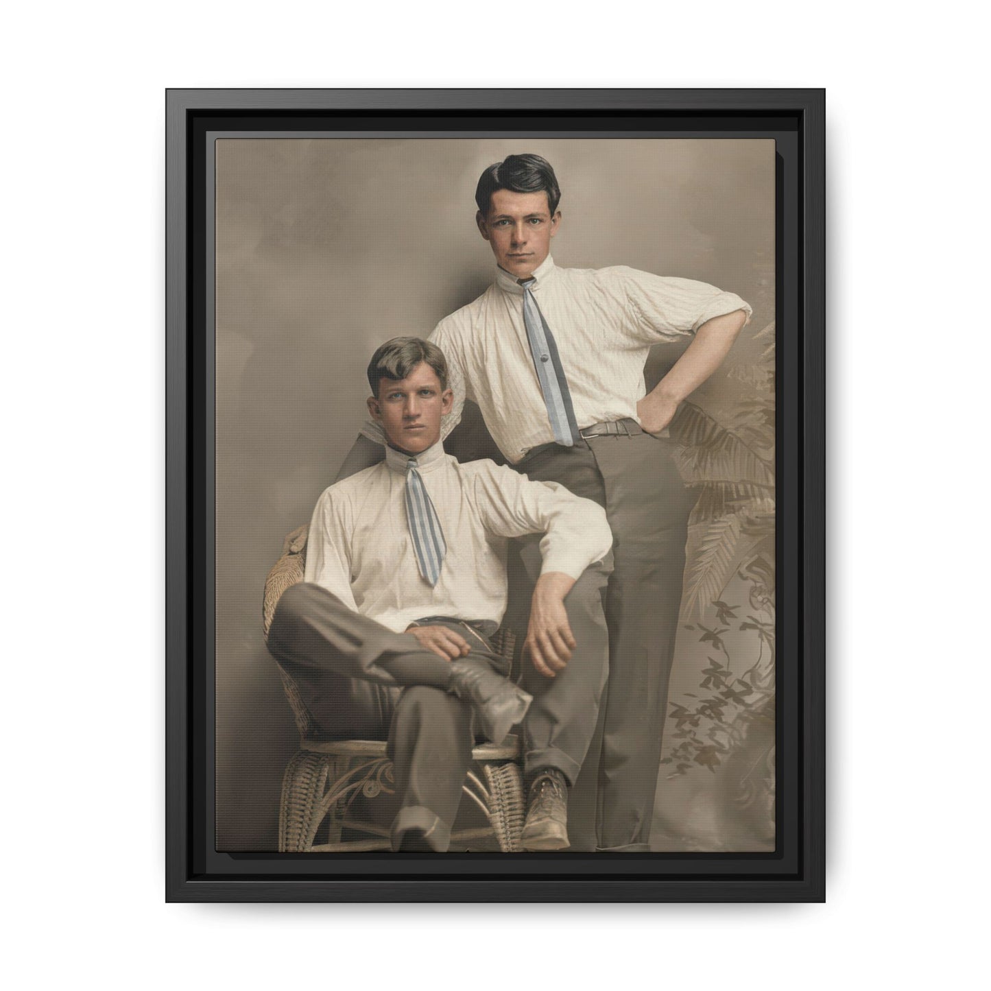 Vintage studio double portrait of two young men in light high-collared shirts with one seated in a wicker chair and one standing