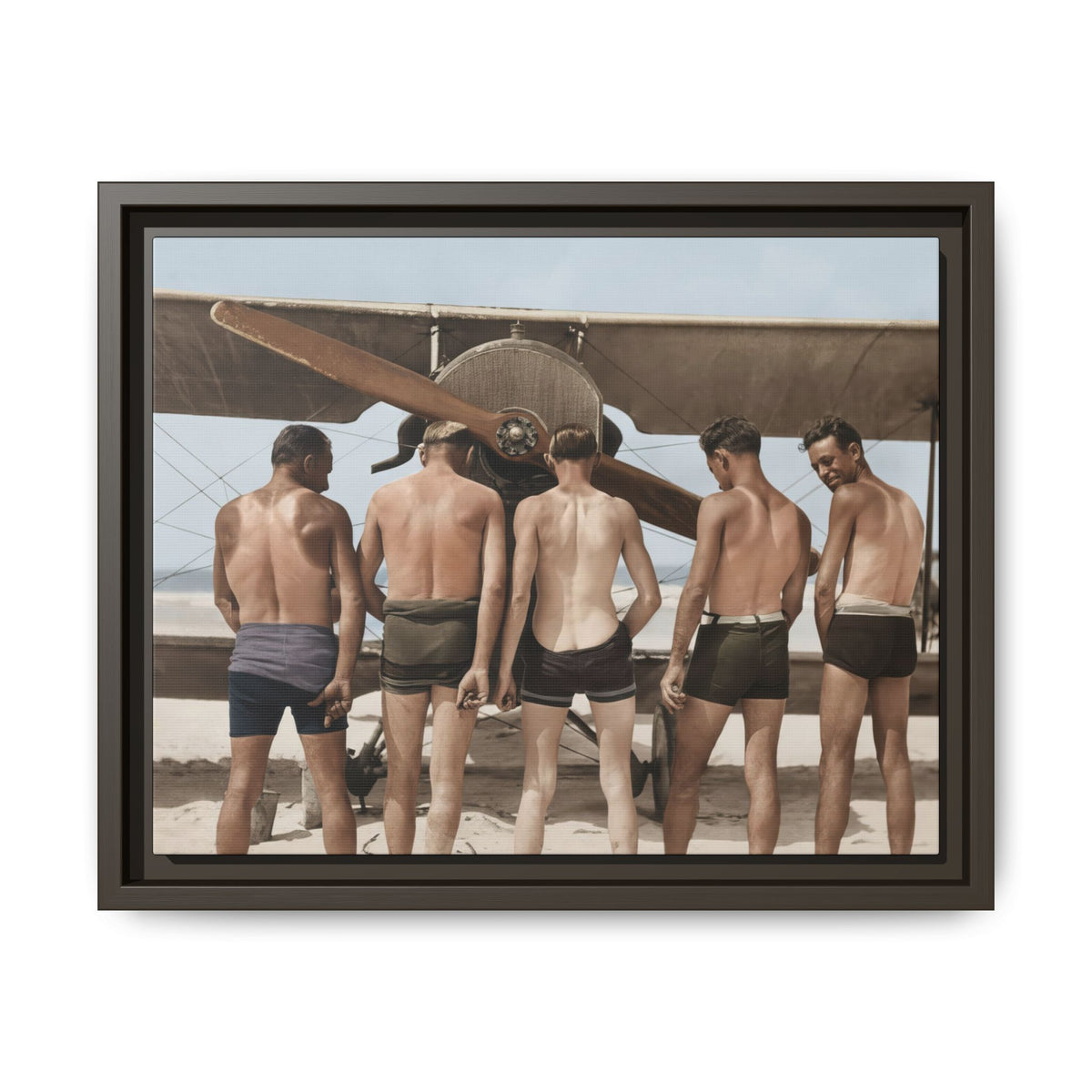 Horizontal aviation photograph with crossing bracing wires, a row of five men, and a smaller background figure under the left wing.