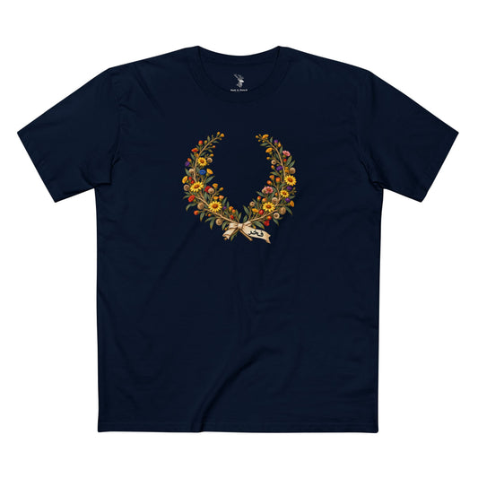 Dark-colored Kuwaiti Pride T-shirt with golden arfaj branches forming a laurel-style wreath, subtle Pride-colored blossoms, and contrasting Arabic text فخر below.