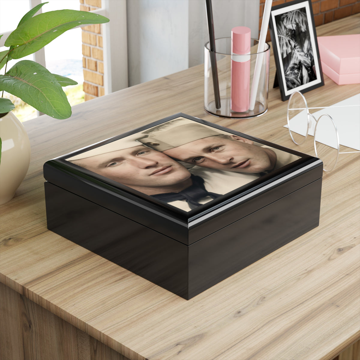 Overhead view of a keepsake box lid showing two men with heads touching, one in a white sailor cap and one in a light garrison cap.