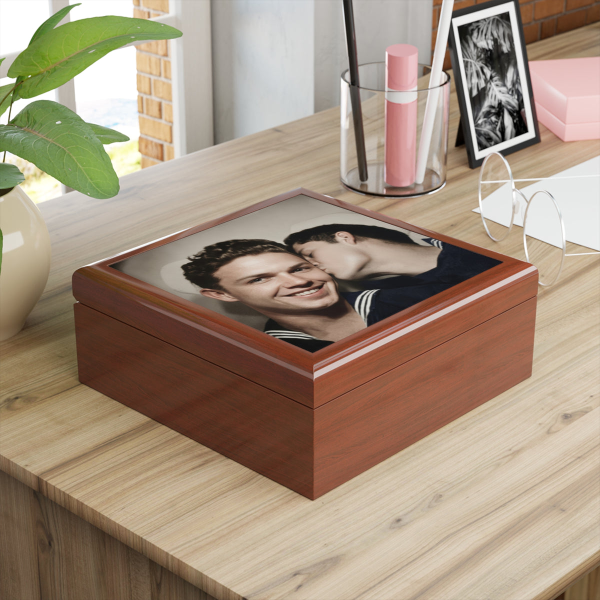 Reddish-brown keepsake box on a wooden dresser, featuring a smiling man and another kissing his cheek in a vintage sailor portrait.
