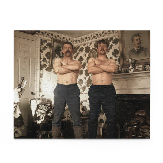 Two bare-chested mustached men with folded arms in a floral-wallpapered room with framed portraits, a fireplace, and sporting equipment.