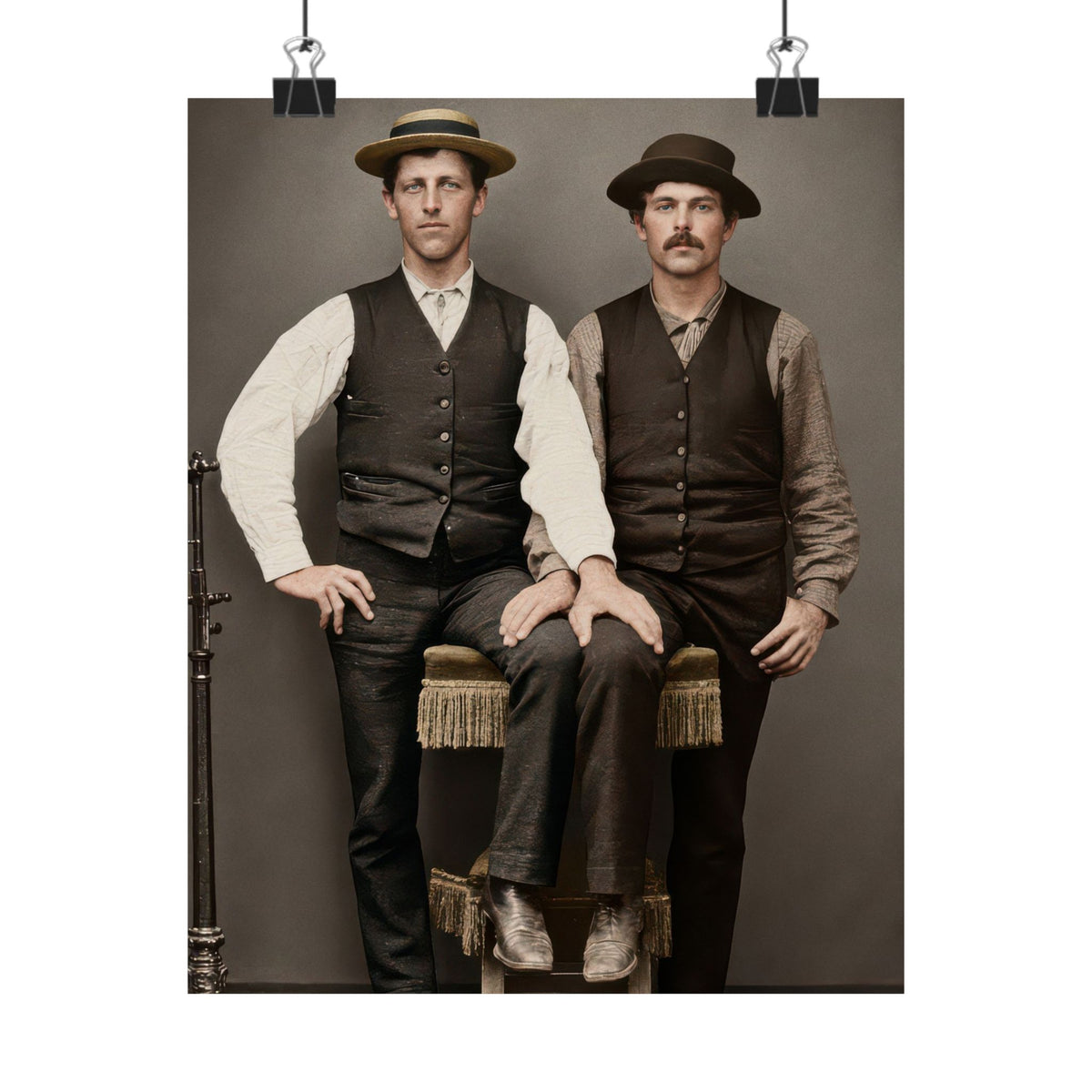 Restored Victorian photograph showing a straw boater, dark felt hat, buttoned waistcoats, fringed upholstery, and a metal studio fixture.