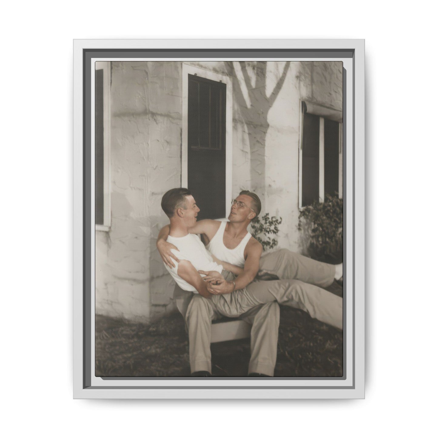 Historical double portrait showing two men in sleeveless shirts seated in a relaxed pose outdoors
