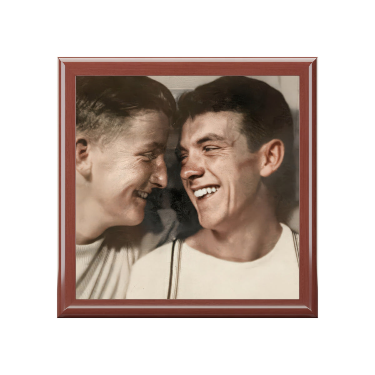 Overhead view of a keepsake box lid showing two men smiling at each other in light shirts, with striped suspenders on the right.