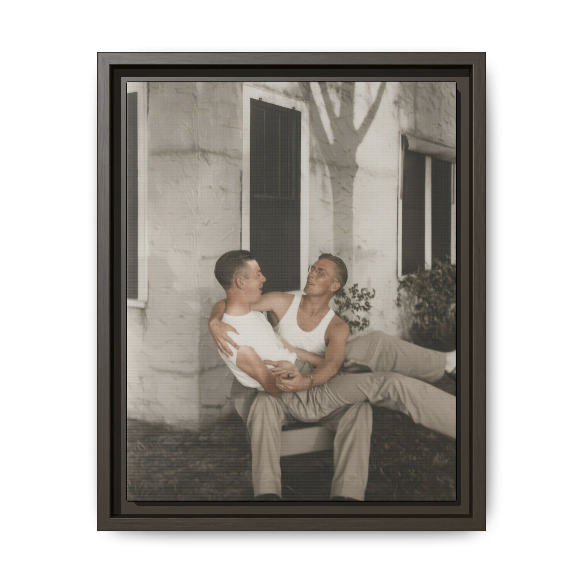 Historical double portrait showing two men in sleeveless shirts seated in a relaxed pose outdoors