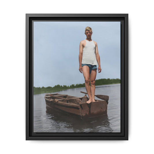 Man standing barefoot in small wooden boat on calm water in early 20th-century photograph 