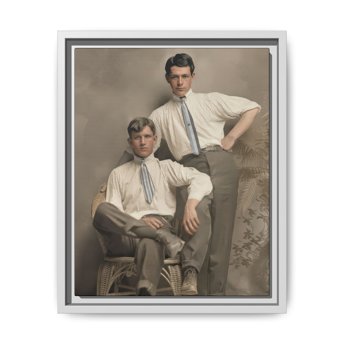 Early 20th century style studio portrait of two men posed together with a wicker chair and neutral painted background