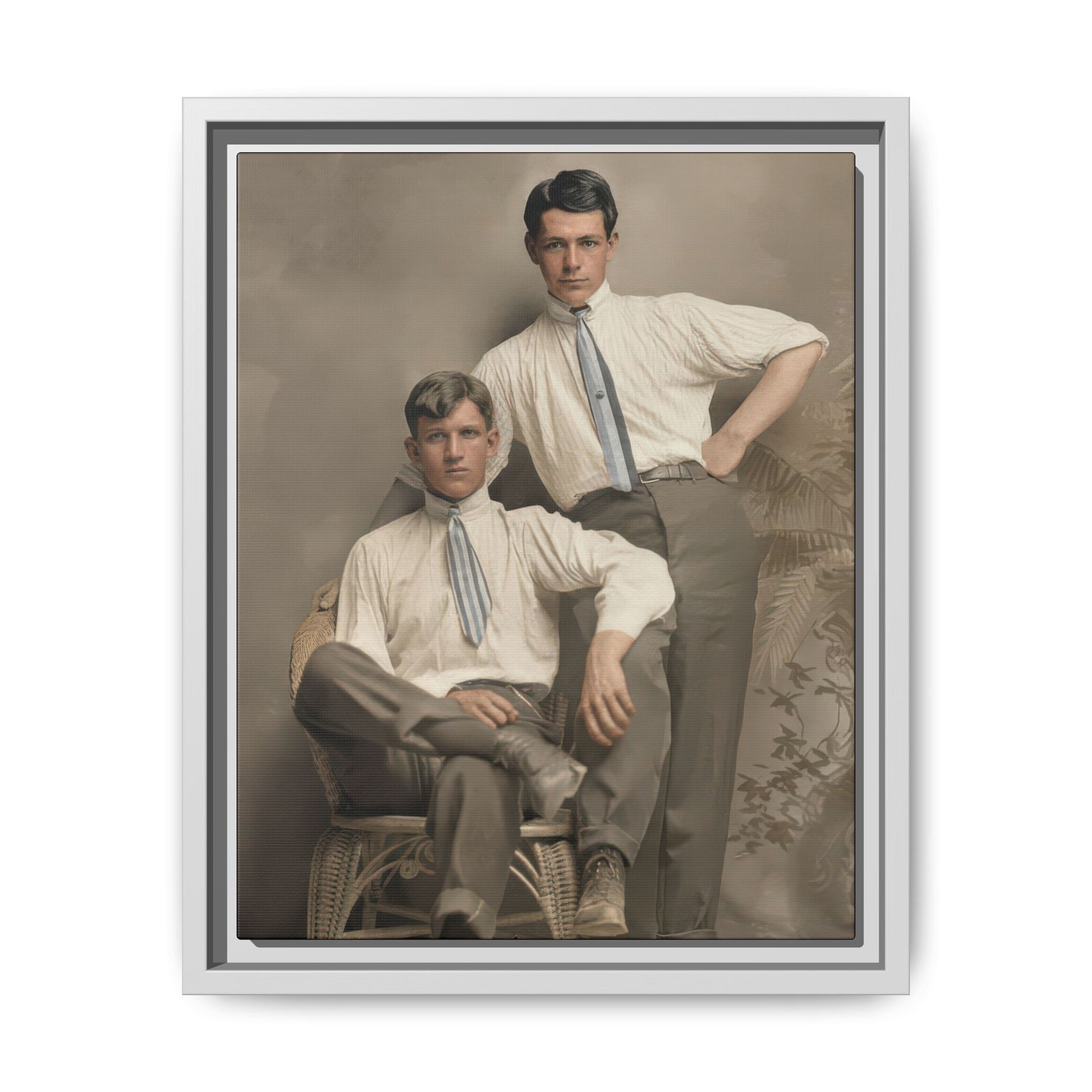 Early 20th century style studio portrait of two men posed together with a wicker chair and neutral painted background