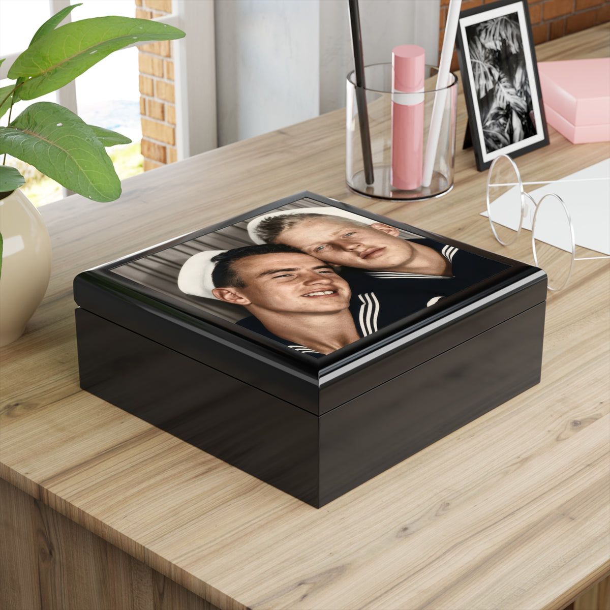  Angled view of a glossy wooden keepsake box with two sailors in dark uniforms, white caps, and a close photobooth pose on its lid.