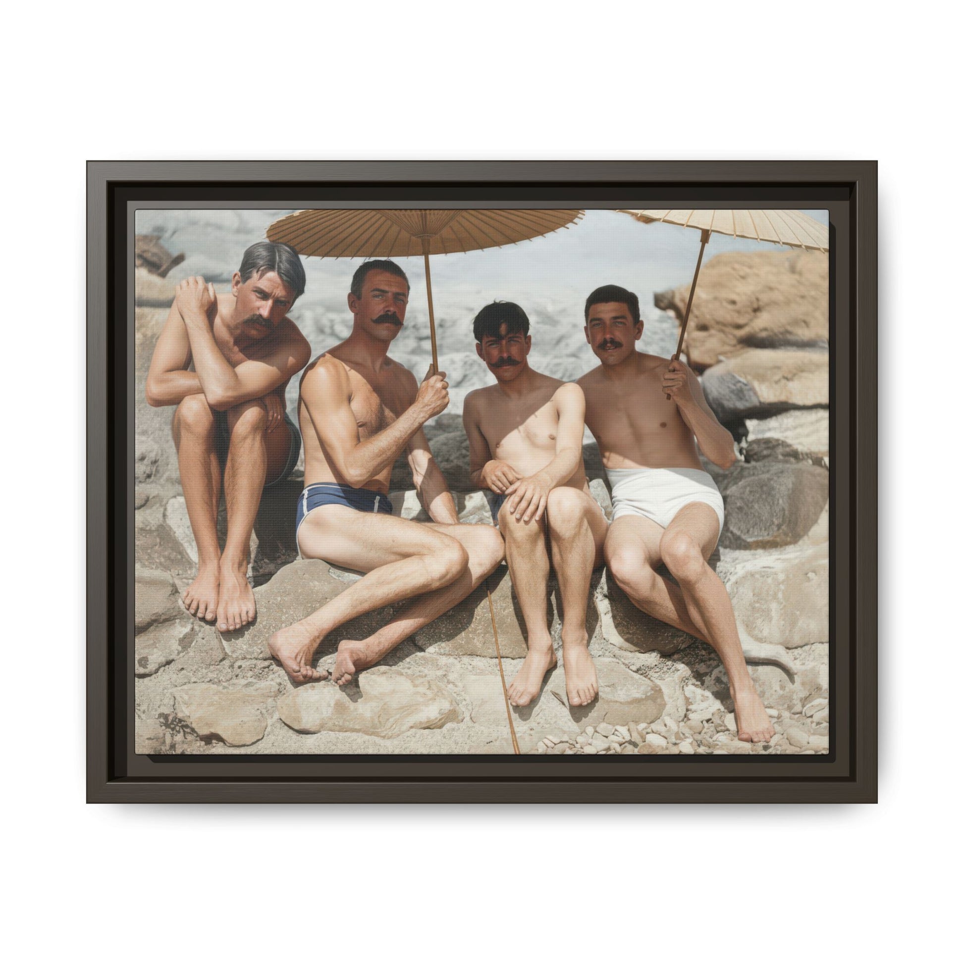 Vintage coastal wall art featuring four men in swimwear seated among rocks by the shore 