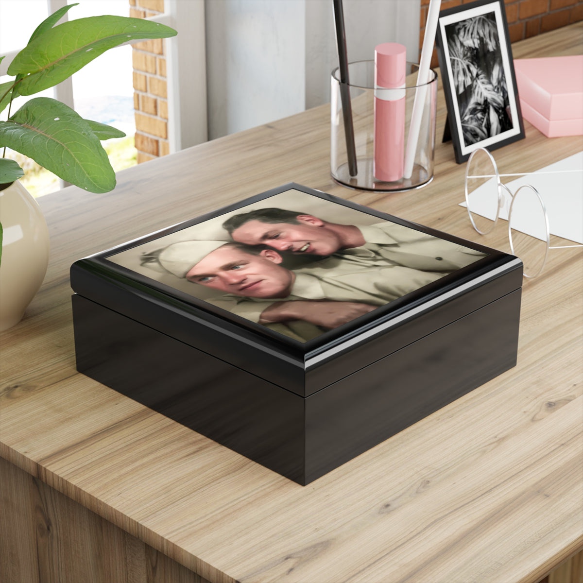 Overhead view of a keepsake box lid showing two uniformed men, one smiling with an arm around the other, who wears a pale cap.