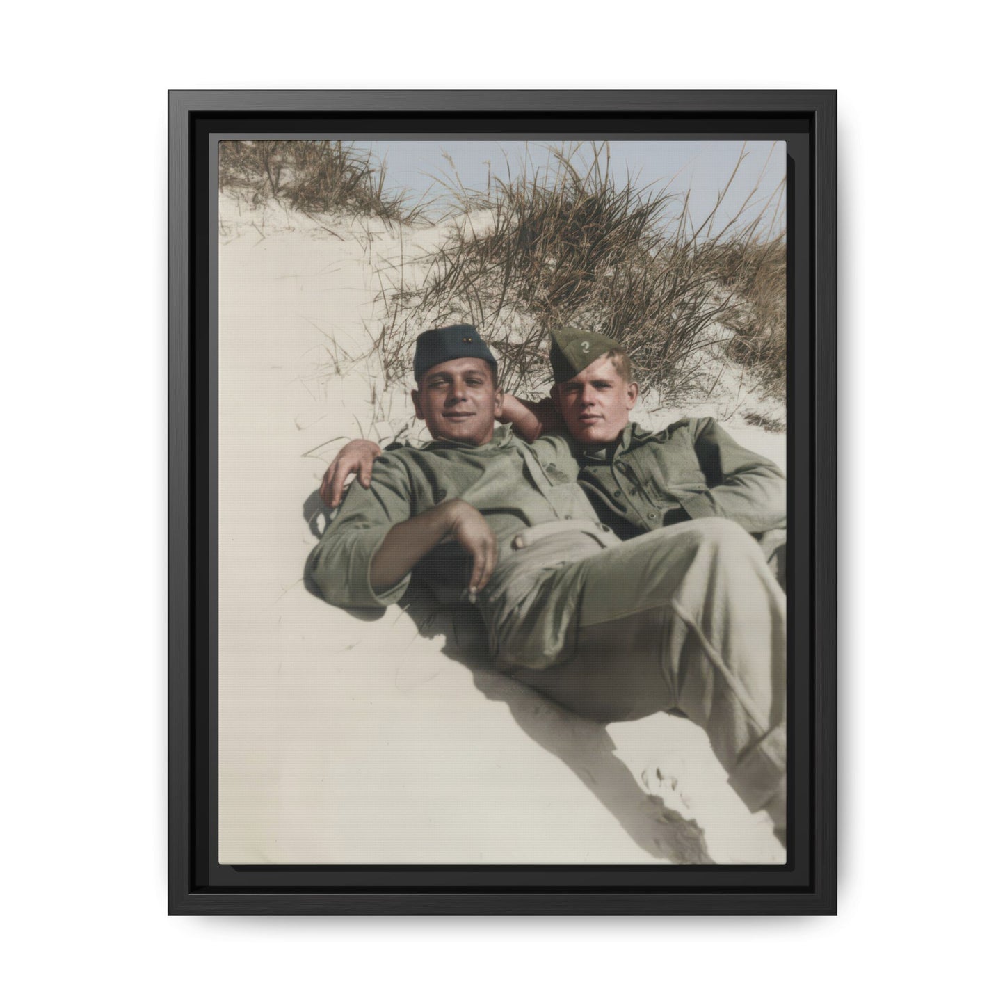 Vintage photograph of two soldiers reclining together on a sand dune with tall grasses and open sky