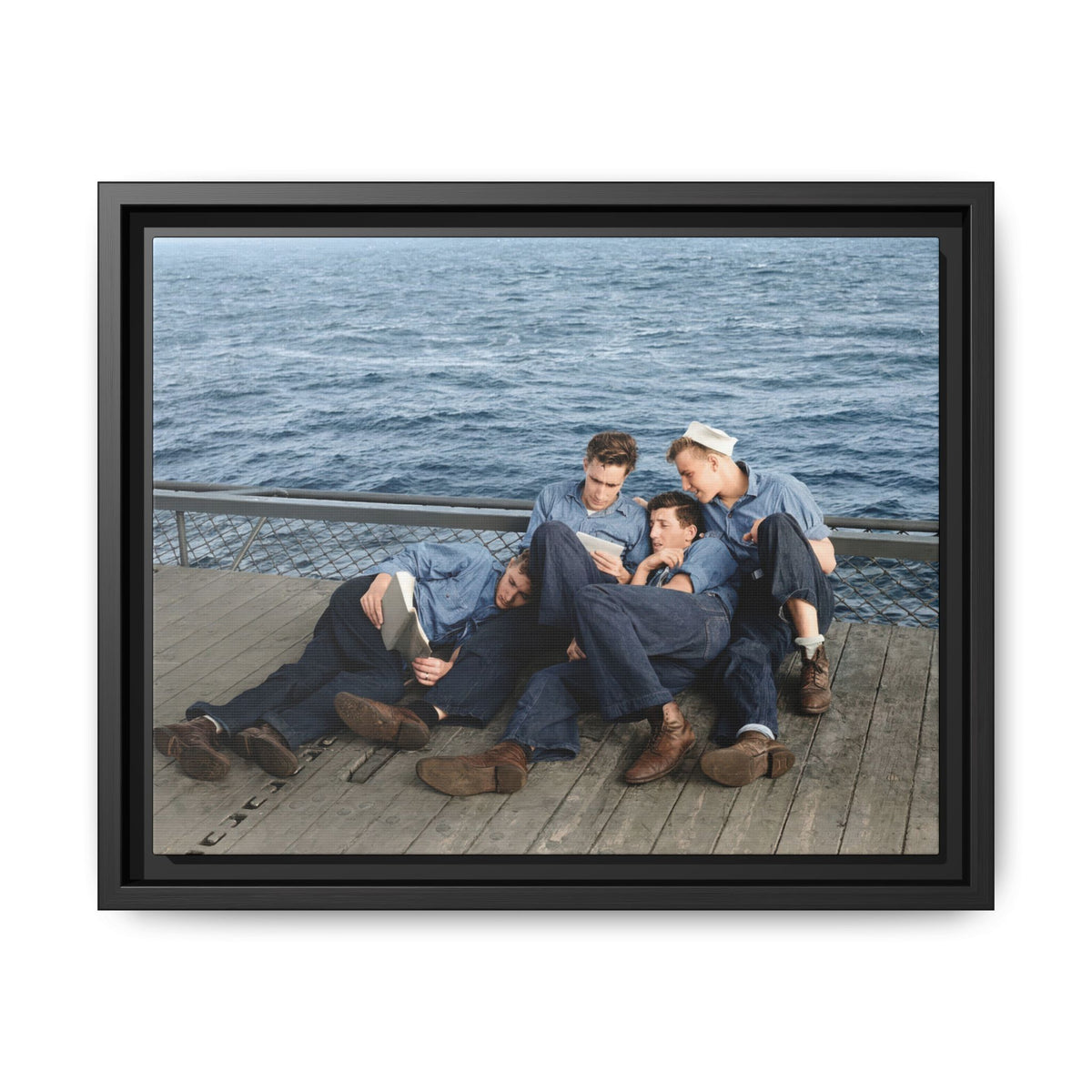 Restored colorized photograph of four sailors reclining on a wooden ship deck with an open book and smaller reading material.