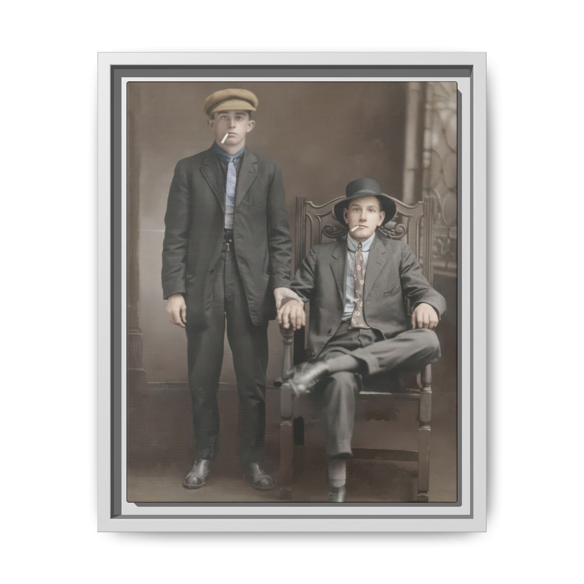 Vintage studio photograph of two men in dark tailored clothing against a painted backdrop
