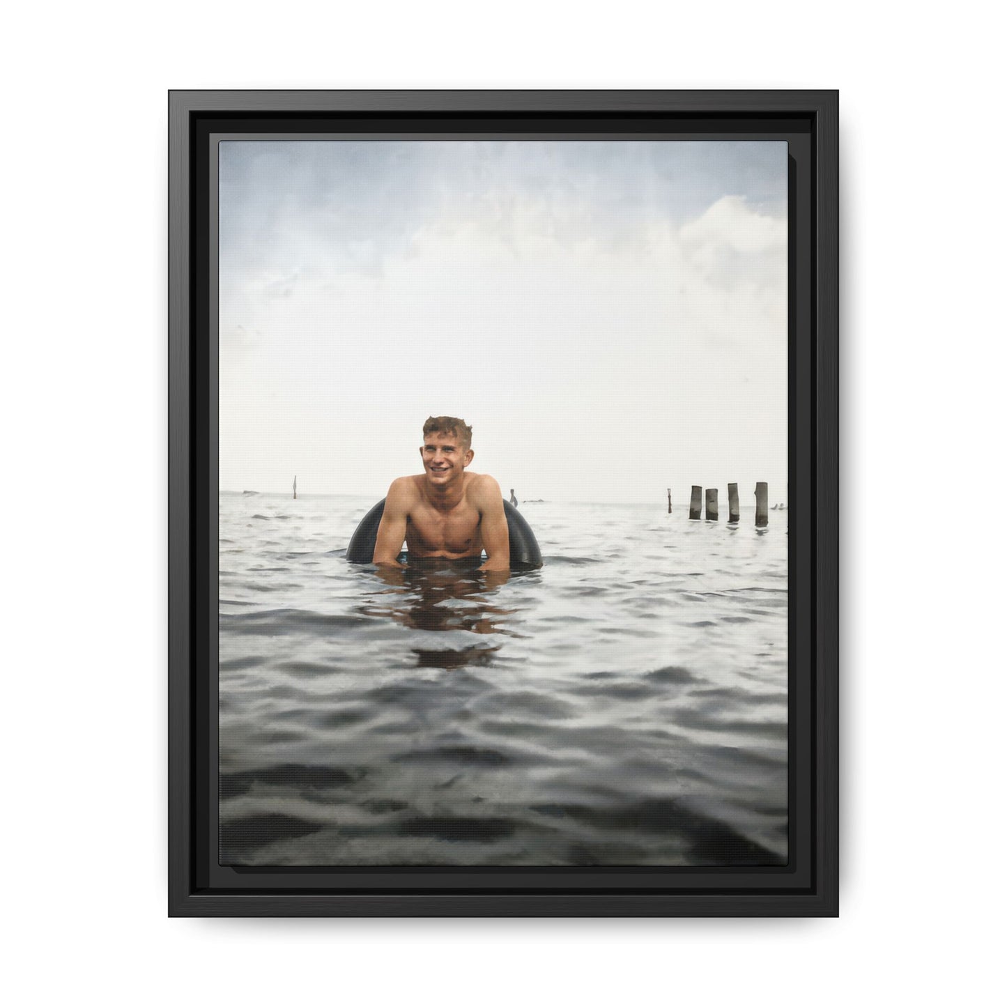 Restored vintage photograph of a young man in open water with an inner tube 