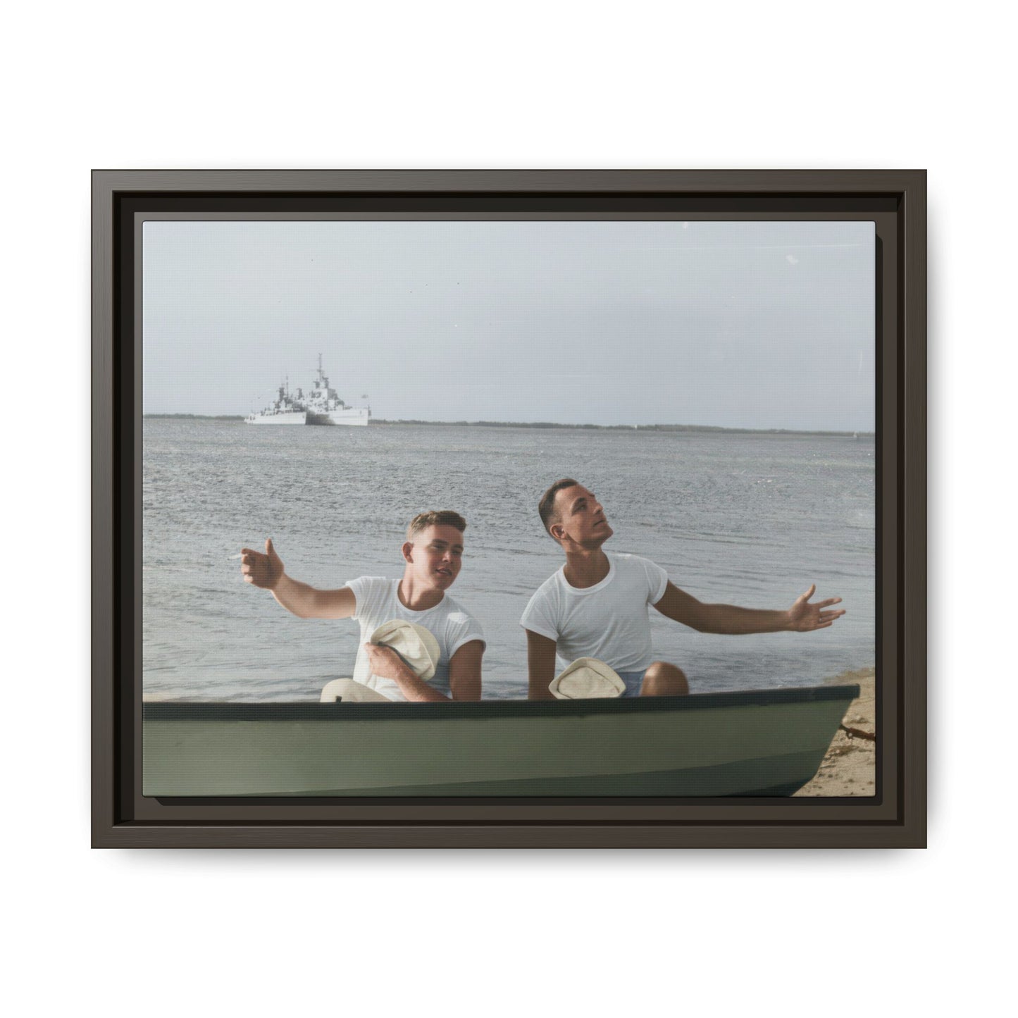 Mid-century outdoor portrait of two sailors seated together in a boat beside a waterfront shoreline