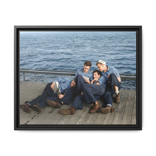 Four men in short-sleeved shirts and dark trousers gathered beside a mesh barrier, with one white sailor cap and open water behind them.