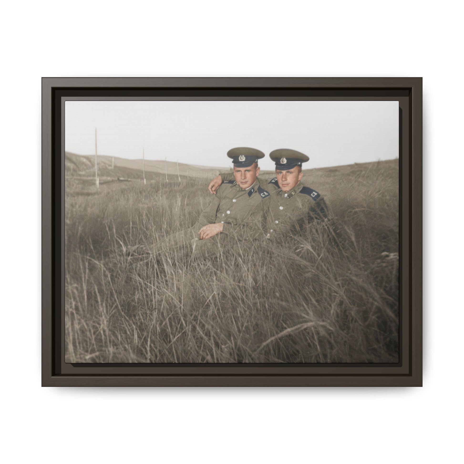 Vintage outdoor photograph of two uniformed sitters posed closely in a grassy landscape