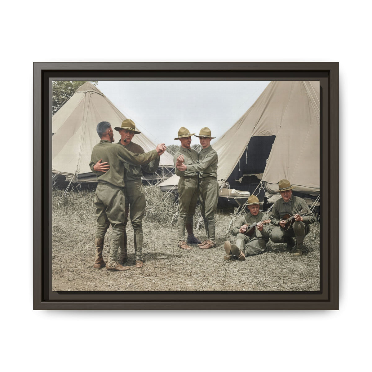 Two pairs of men dance while two seated men hold string instruments before large canvas tents in a restored 1917 camp photograph.
