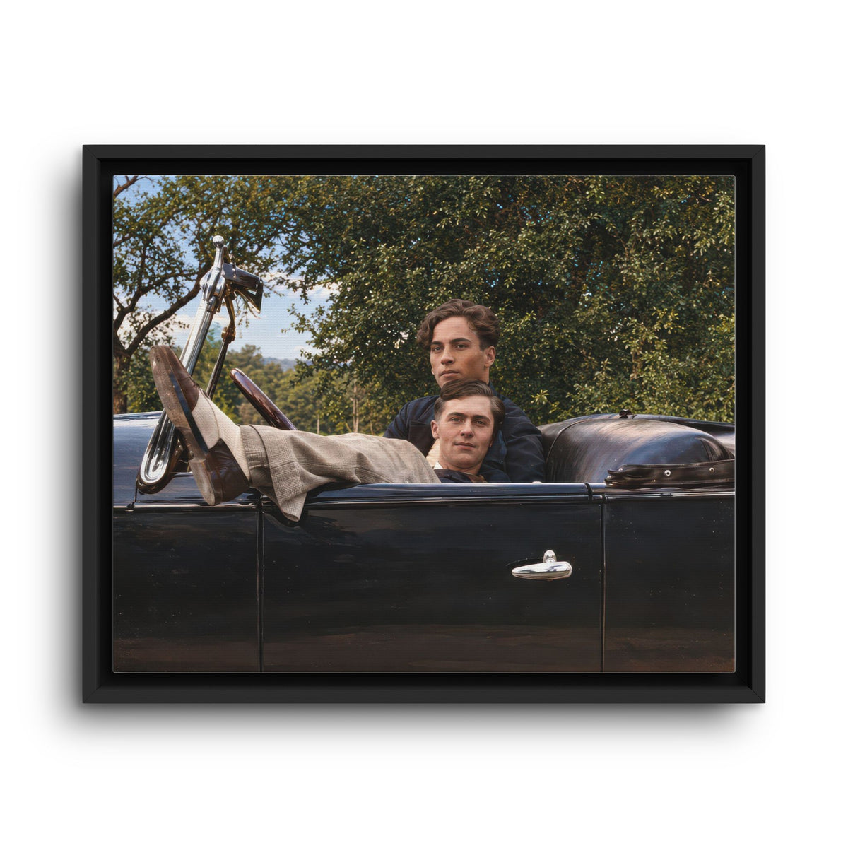 2.	Close view of two men in a vintage convertible, one reclining across the front seat.