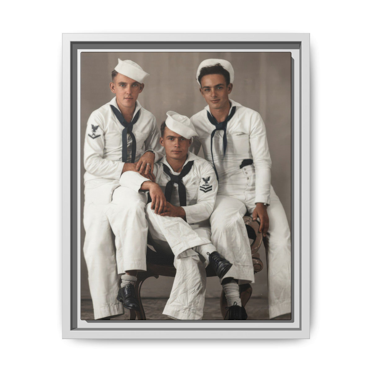 Vertical historical group portrait with a lower central sitter between two men in white uniforms, with sleeve insignia and dark shoes visible.