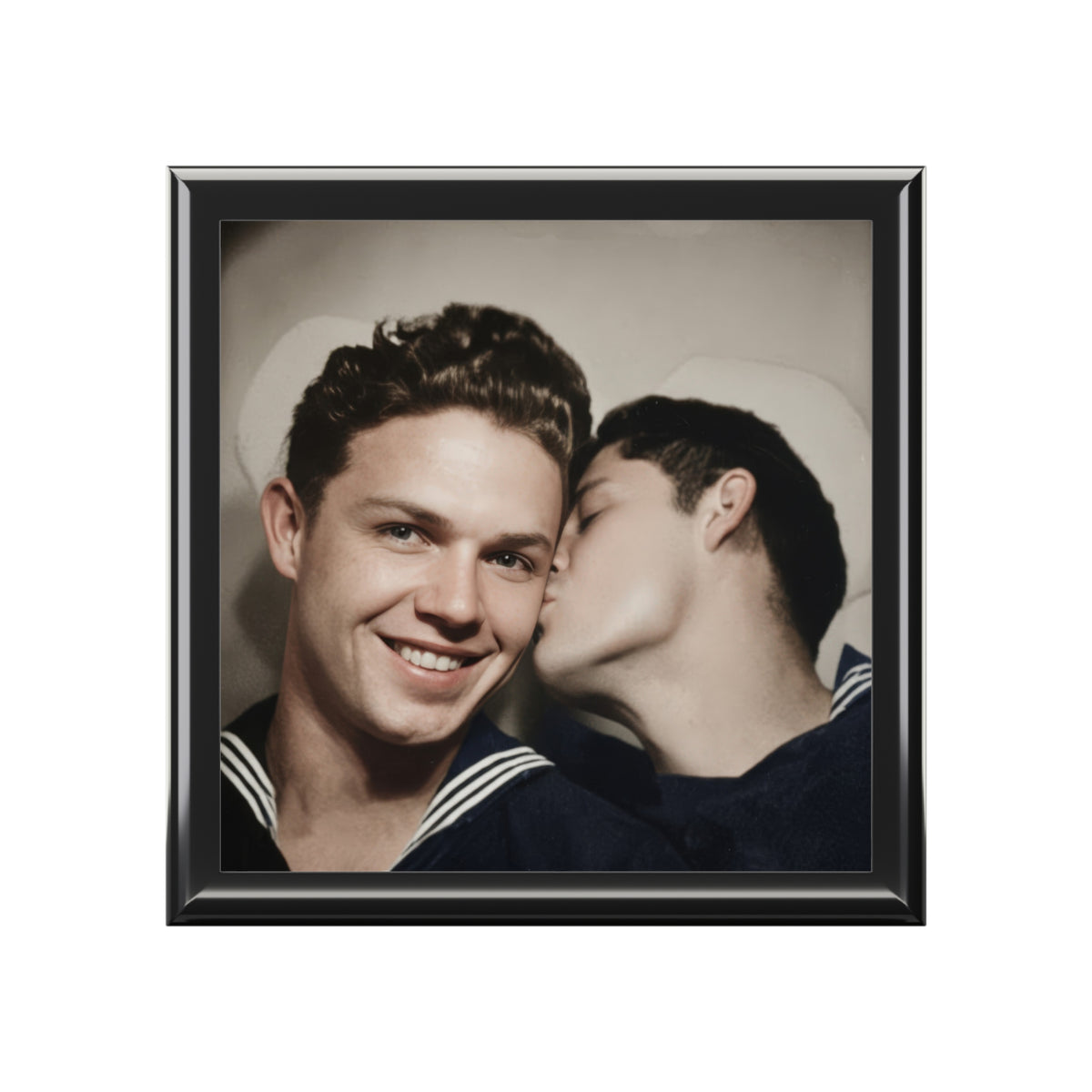 Black keepsake box on a wooden dresser, with a vintage portrait of two men in sailor uniforms sharing a cheek kiss on the lid.