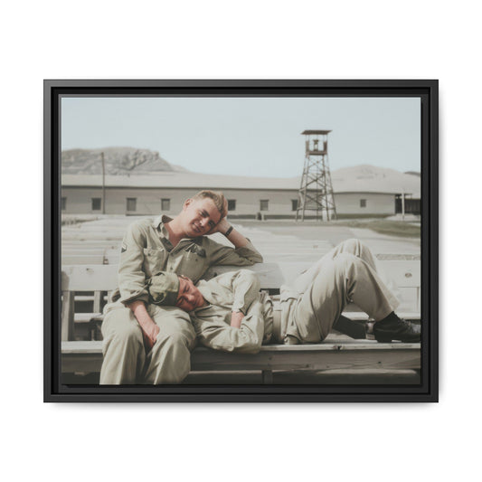 Historical military portrait showing two soldiers in relaxed pose on a base with barracks and open yard