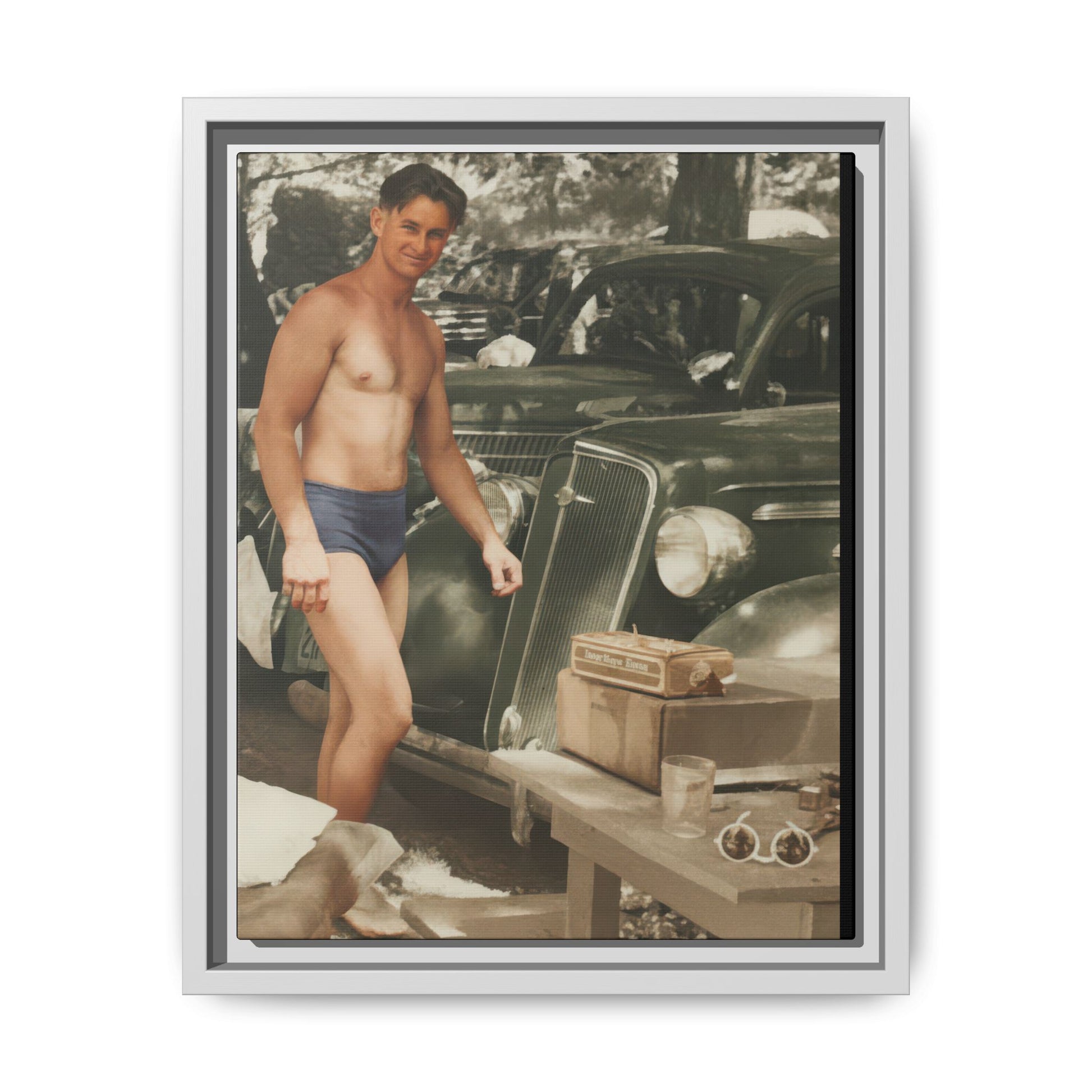 Vintage recreation wall art featuring a man in swimwear standing near automobiles in dappled shade 