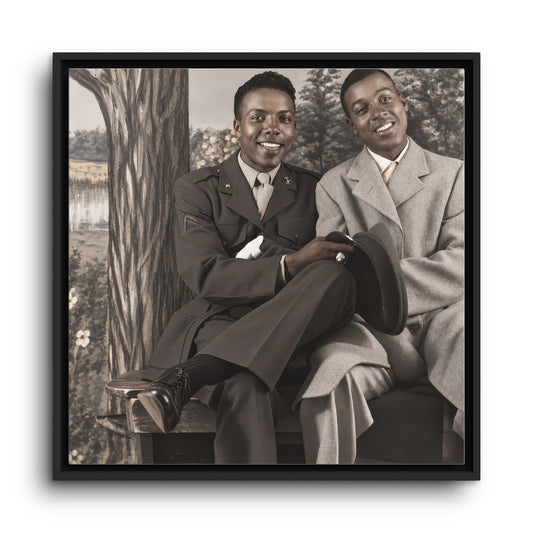 Historical double portrait of two Black men smiling toward the camera, with military-style insignia, a brimmed hat, and a scenic backdrop.