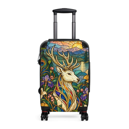 The Jeweled Sentinel suitcase featuring an ivory stag with golden antlers surrounded by jewel-toned stained-glass irises, lilies, peacock feathers, mountains, and a sunrise.